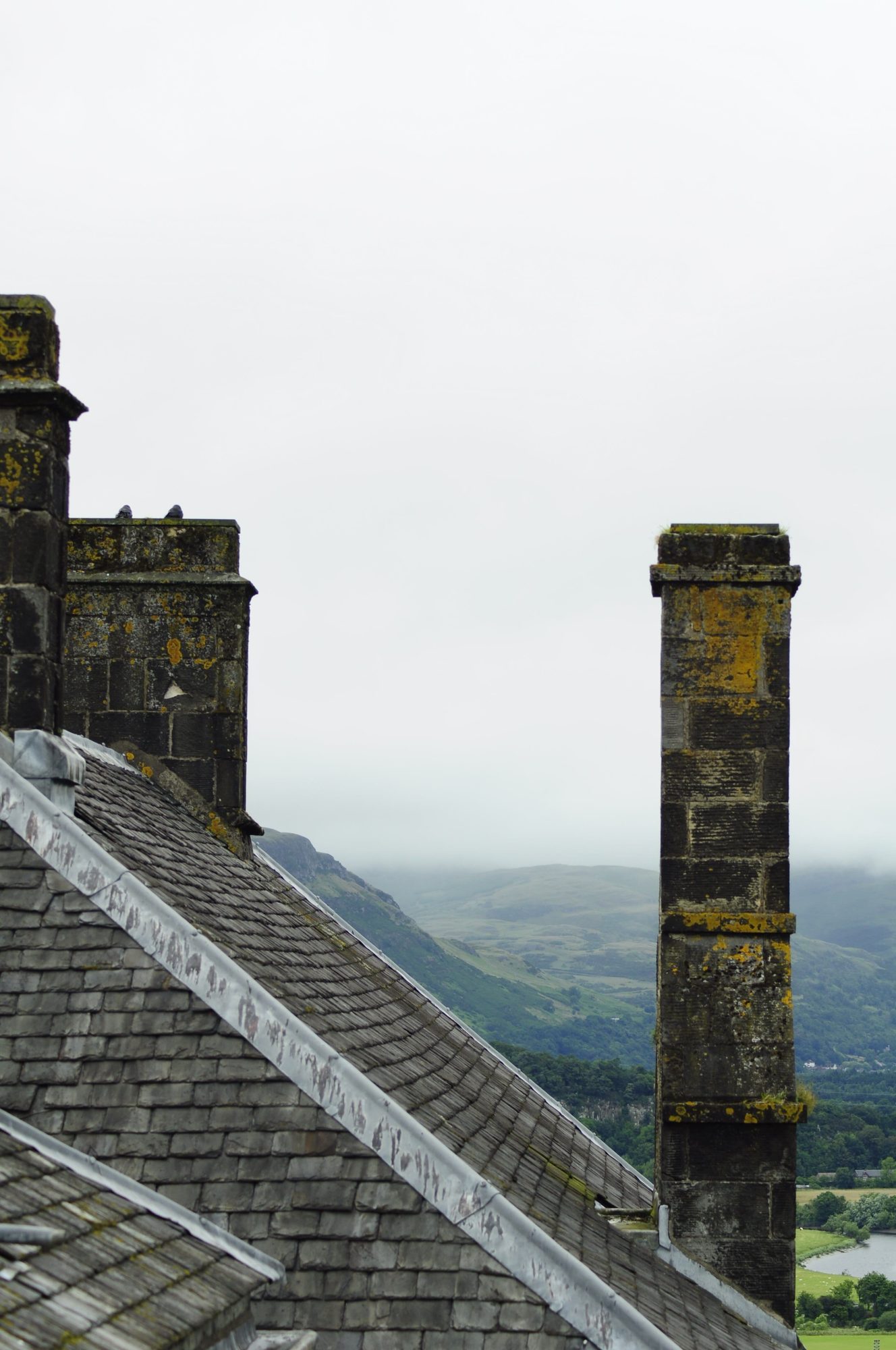 A misty Highland hillside with a weathered stone chimney and slate roof, evoking the landscape slate was historically quarried from
